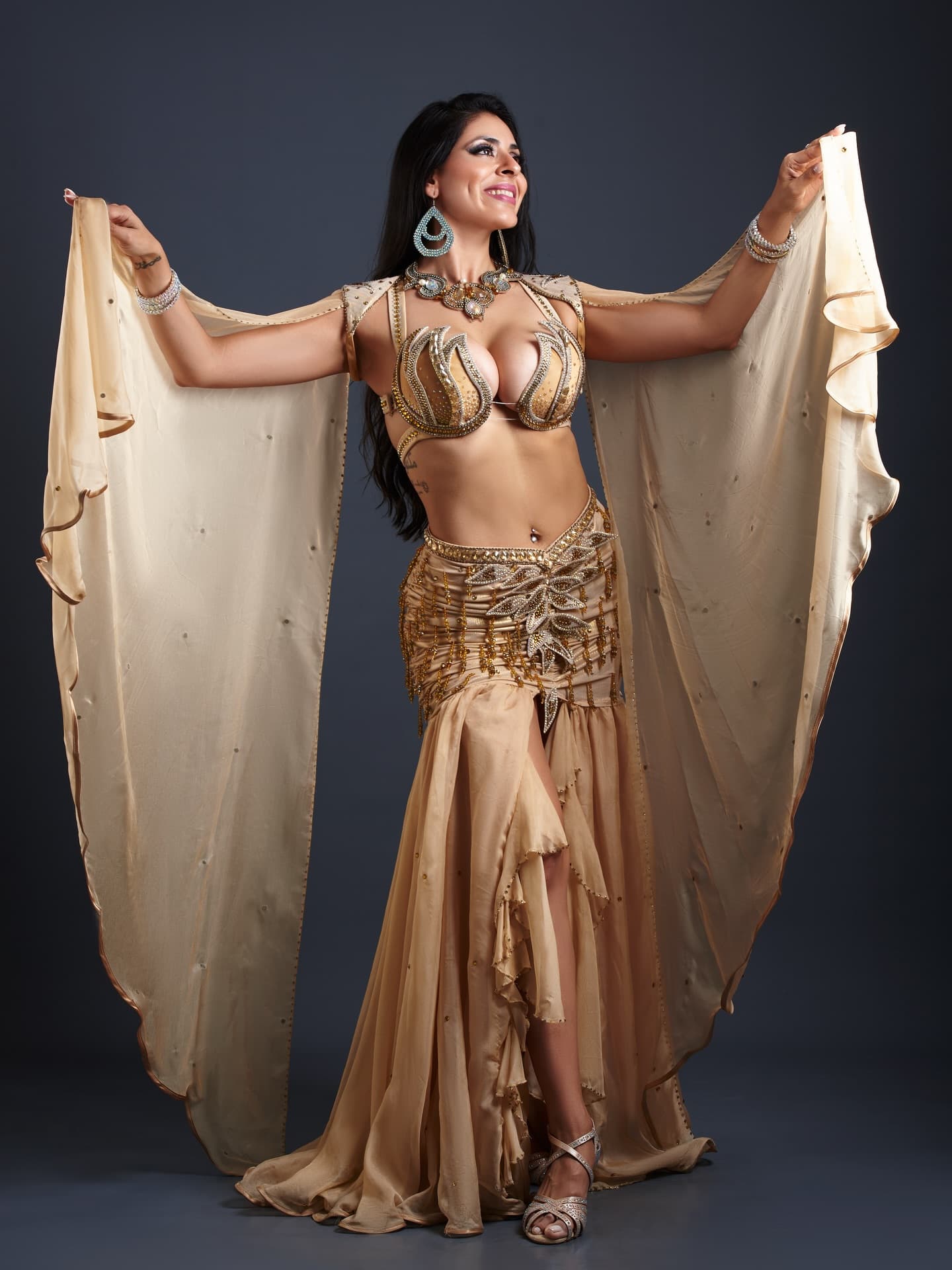 Nabilla in a gold belly dance costume posing with a veil.   
